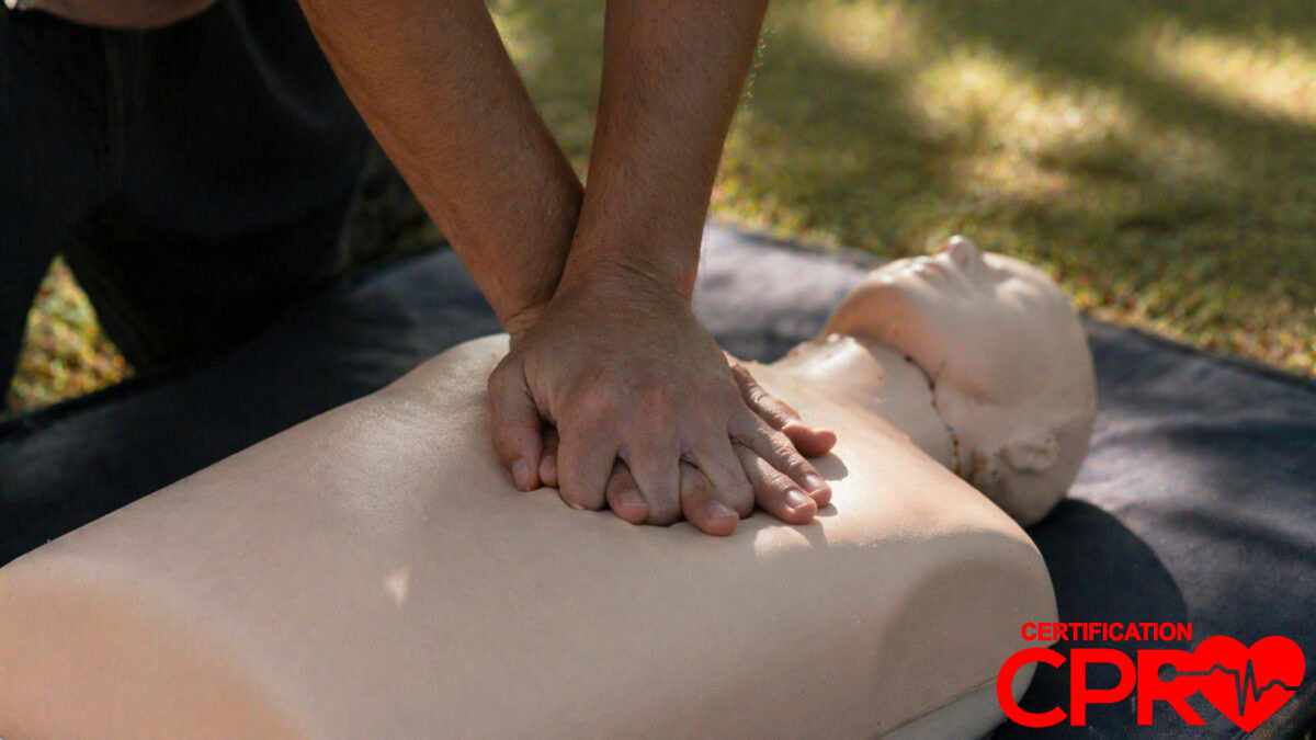 Person performing hands-only CPR on a mannequin outdoors in Boston.
